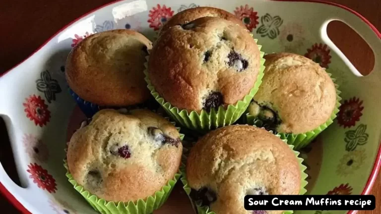 A vibrant display of freshly baked sour cream muffins studded with juicy blueberries, set in colorful muffin liners on a floral-patterned dish.