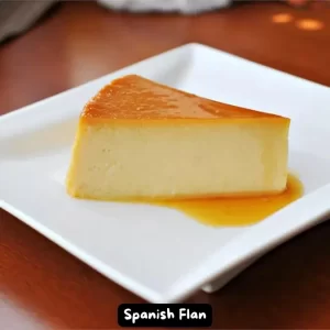 A beautifully caramelized Spanish flan on a white plate with caramel sauce.