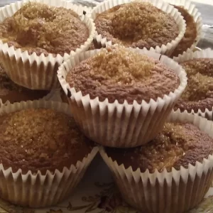 Freshly baked apple and cinnamon cupcakes topped with demerara sugar on a cooling rack.