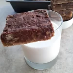 Golden caramel pecan bars topped with smooth melted chocolate, displayed on a cooling rack.