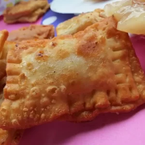 A close-up of golden brown mini apple empanadas with a flaky crust, filled with spiced apple filling.