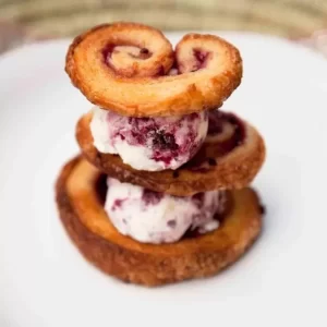 Buttery Palmiers with berry compote and macaron ice-cream served on a dessert plate.