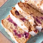 A delicious slice of Raspberry Bakewell Loaf Cake, gluten and dairy free, garnished with toasted almonds.