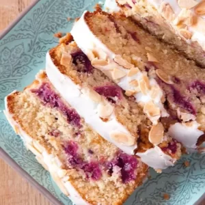 A delicious slice of Raspberry Bakewell Loaf Cake, gluten and dairy free, garnished with toasted almonds.