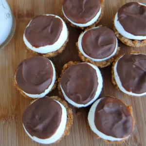 Close-up of S'mores Bites with melted chocolate topping and toasted marshmallow on a graham cracker base.