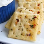 A close-up of golden spicy crackers made with Ranch seasoning and red pepper.