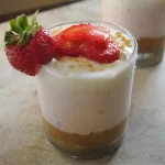 Glass of Strawberry Lemon Cheesecake with marinated strawberries on top